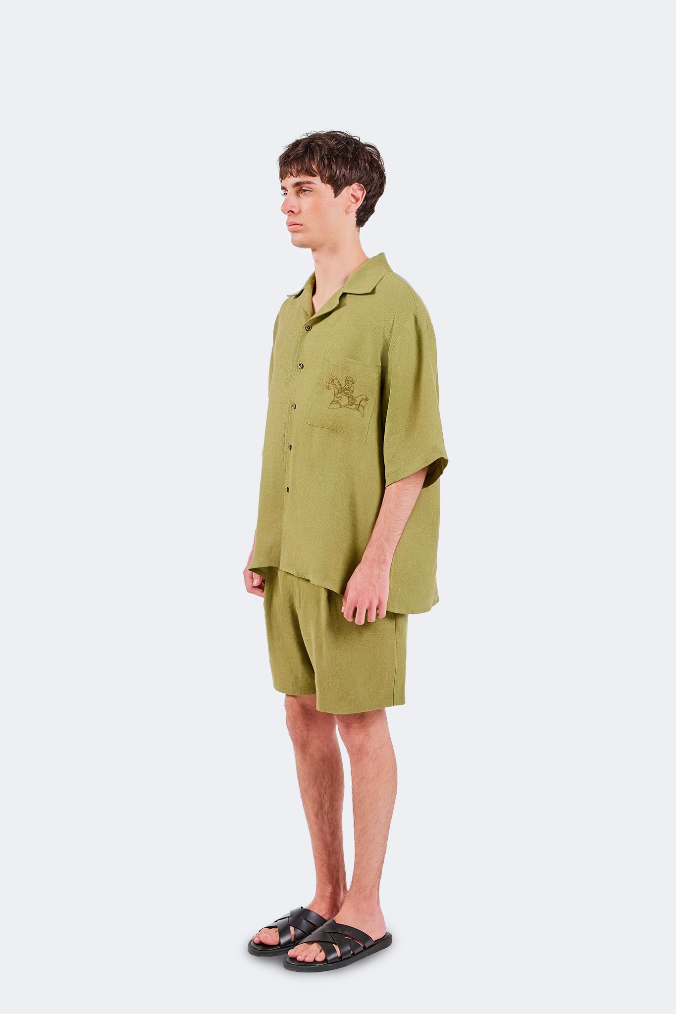 Side view of the San Cristobal Short-Sleeved Shirt in Moss featuring a relaxed linen silhouette and embroidered chest pocket detail.