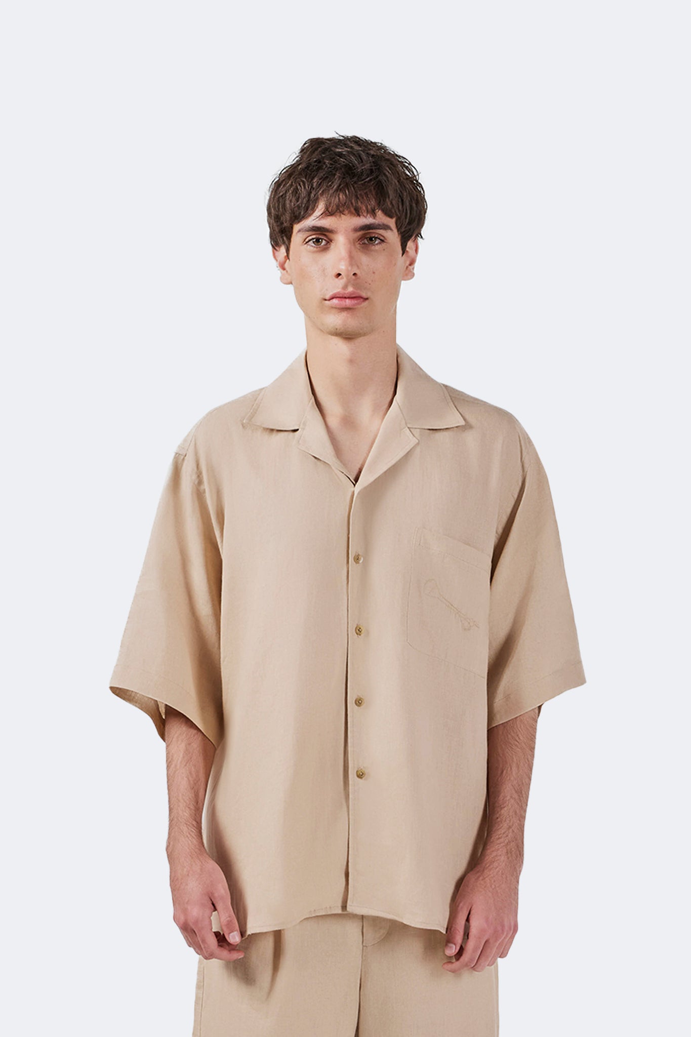 Close-up of the Santa Cruz Short-Sleeved Shirt Ivory featuring the embroidered fish motif on the chest pocket and open.