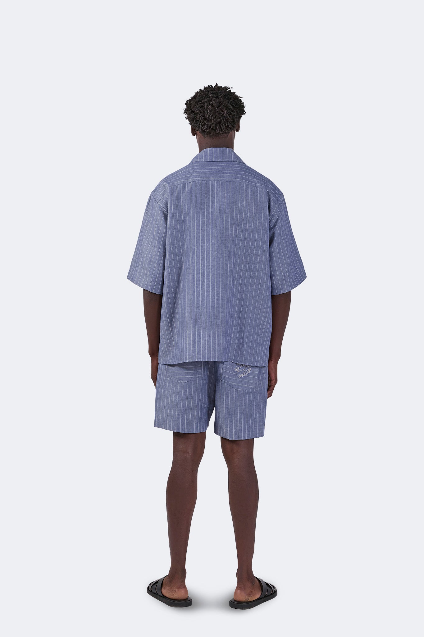 Back view of the Santa Cruz Short-Sleeved Shirt in Indigo Pinstripe paired with coordinating linen shorts, showcasing the relaxed oversized fit and breathable linen construction.