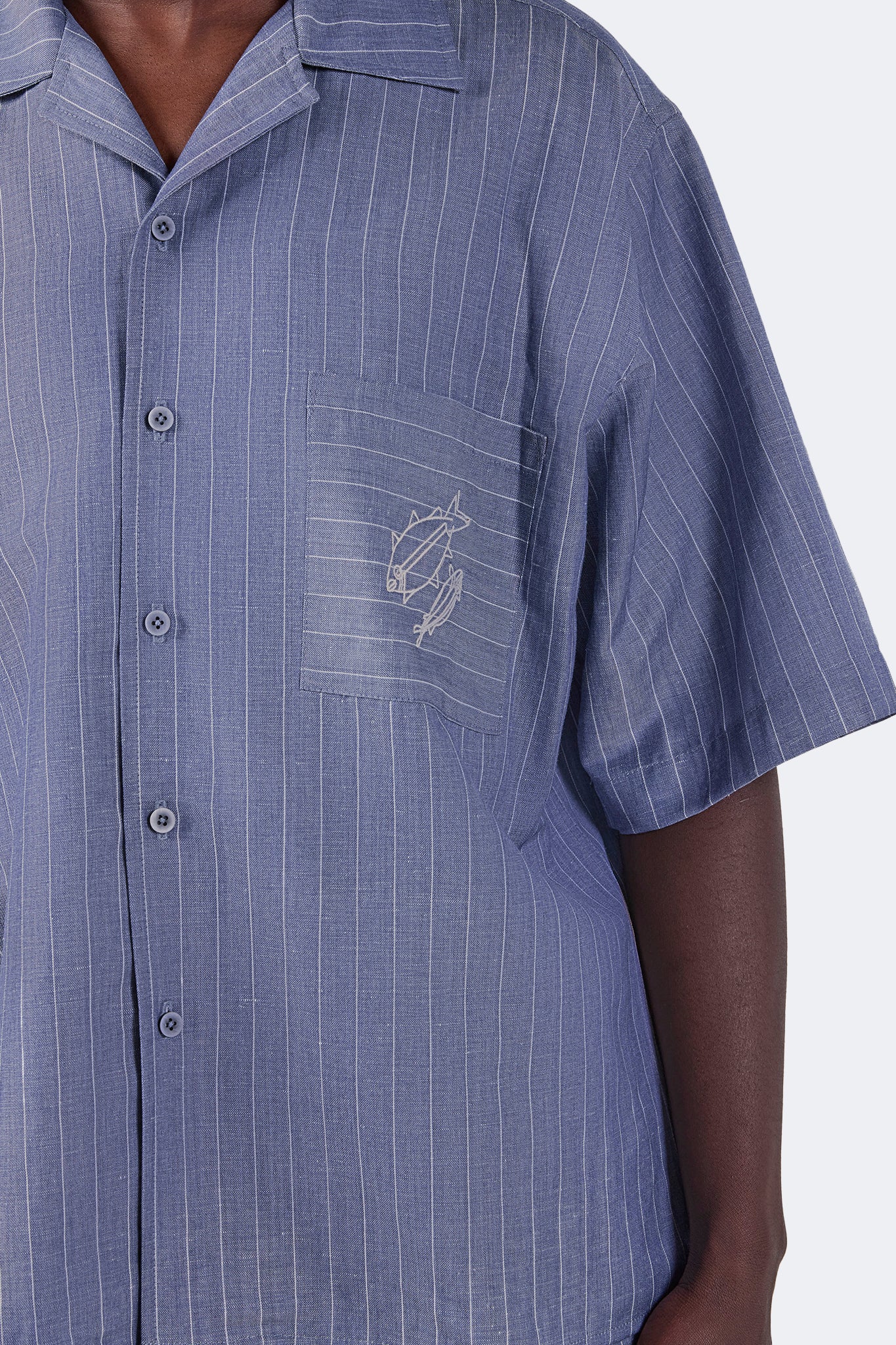 Close-up of the embroidered chest pocket on the Santa Cruz Short-Sleeved Shirt in Indigo Pinstripe highlighting the equestrian-inspired motif and fine linen pinstripes.