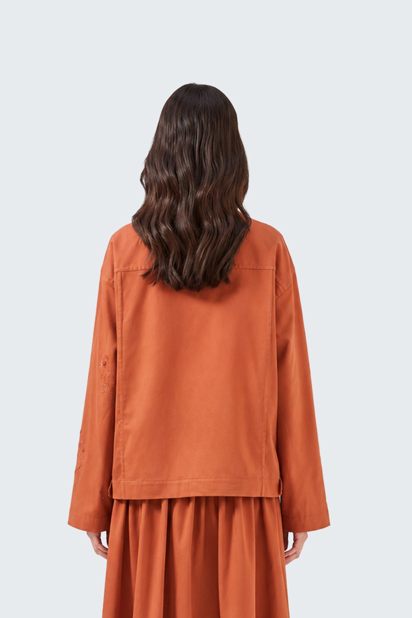 Person wearing a rust-colored outfit on a white background