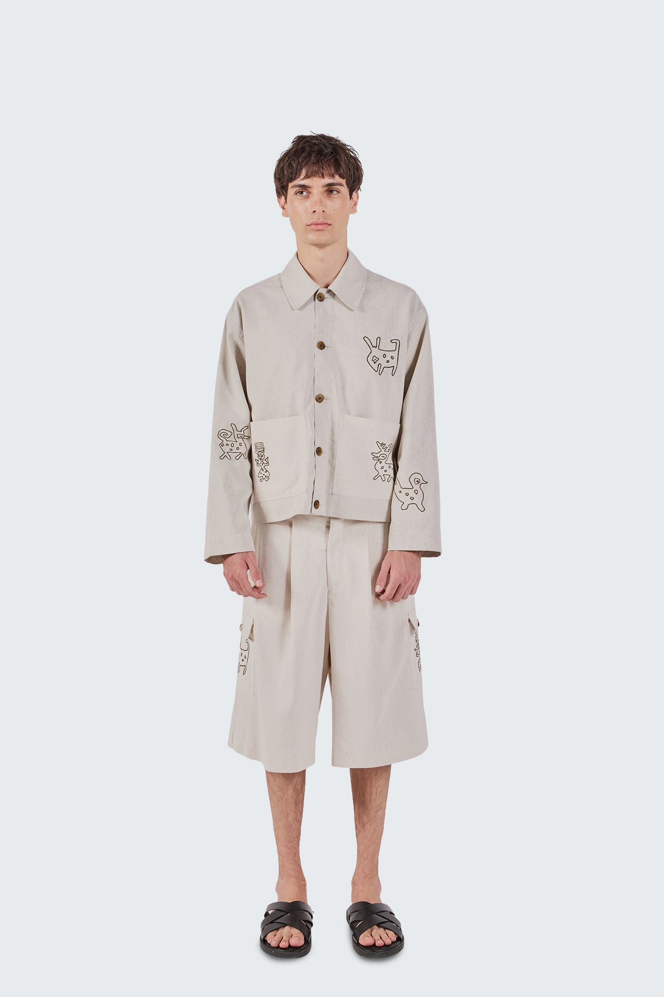 Person wearing a beige embroidered jacket and pants on a white background