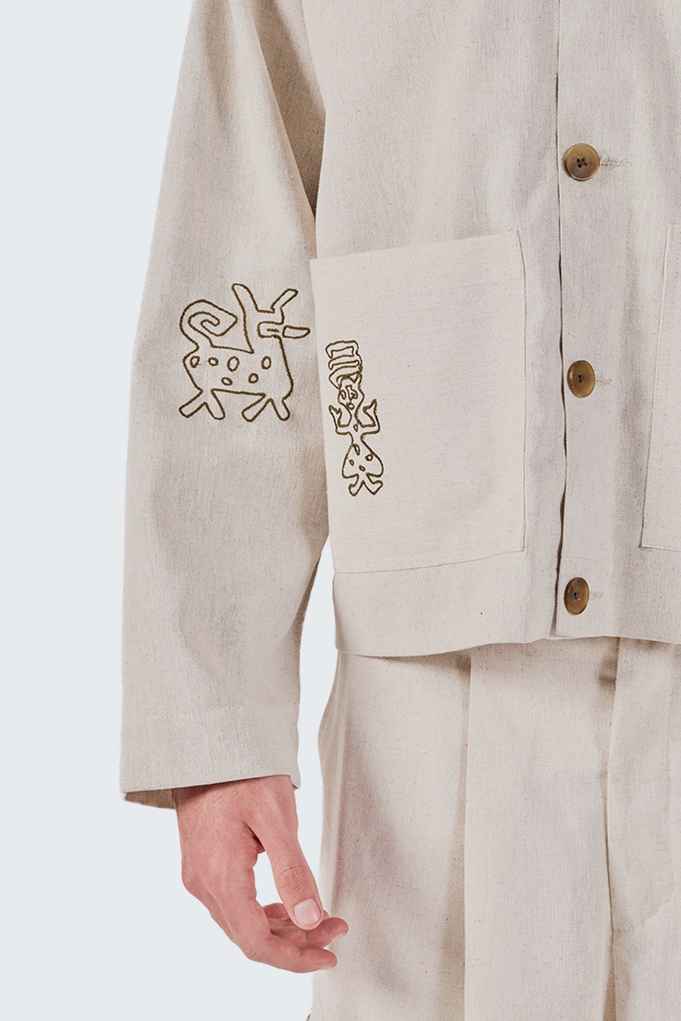 Beige jacket with embroidered designs on a white background