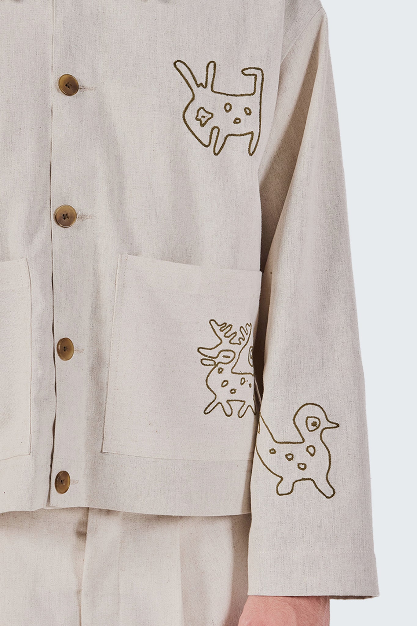 Beige jacket with embroidered animal designs on a plain background