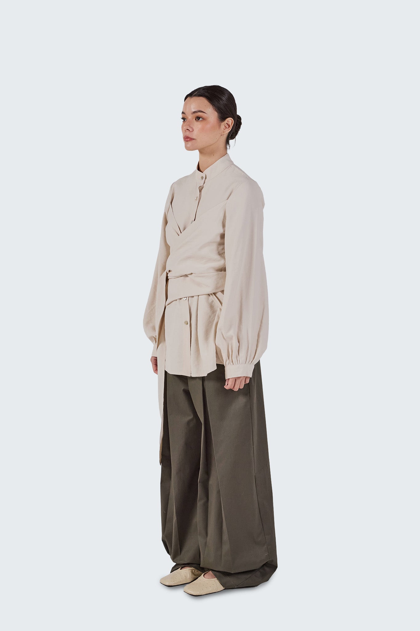 Side view of the Zigze Knotted Blouse in Off-White featuring a wrap-front silhouette, voluminous sleeves, and adjustable waist tie.