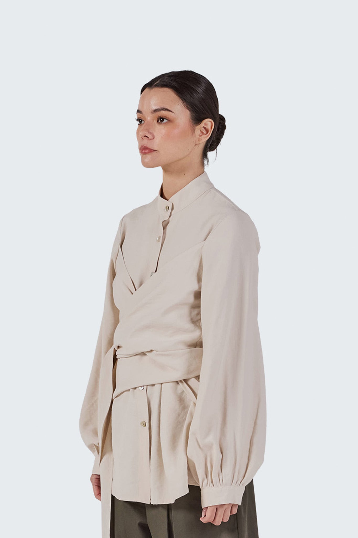 Side portrait view of the Zigze Knotted Blouse highlighting the stand collar, elegant draping, and relaxed tailored silhouette.