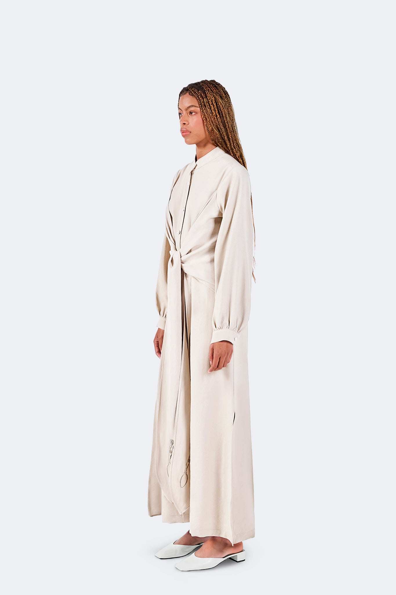 Side view of the Zigze Knotted Dress in Ivory highlighting its fluid drape, architectural silhouette, side slit detail, and elegant proportions.