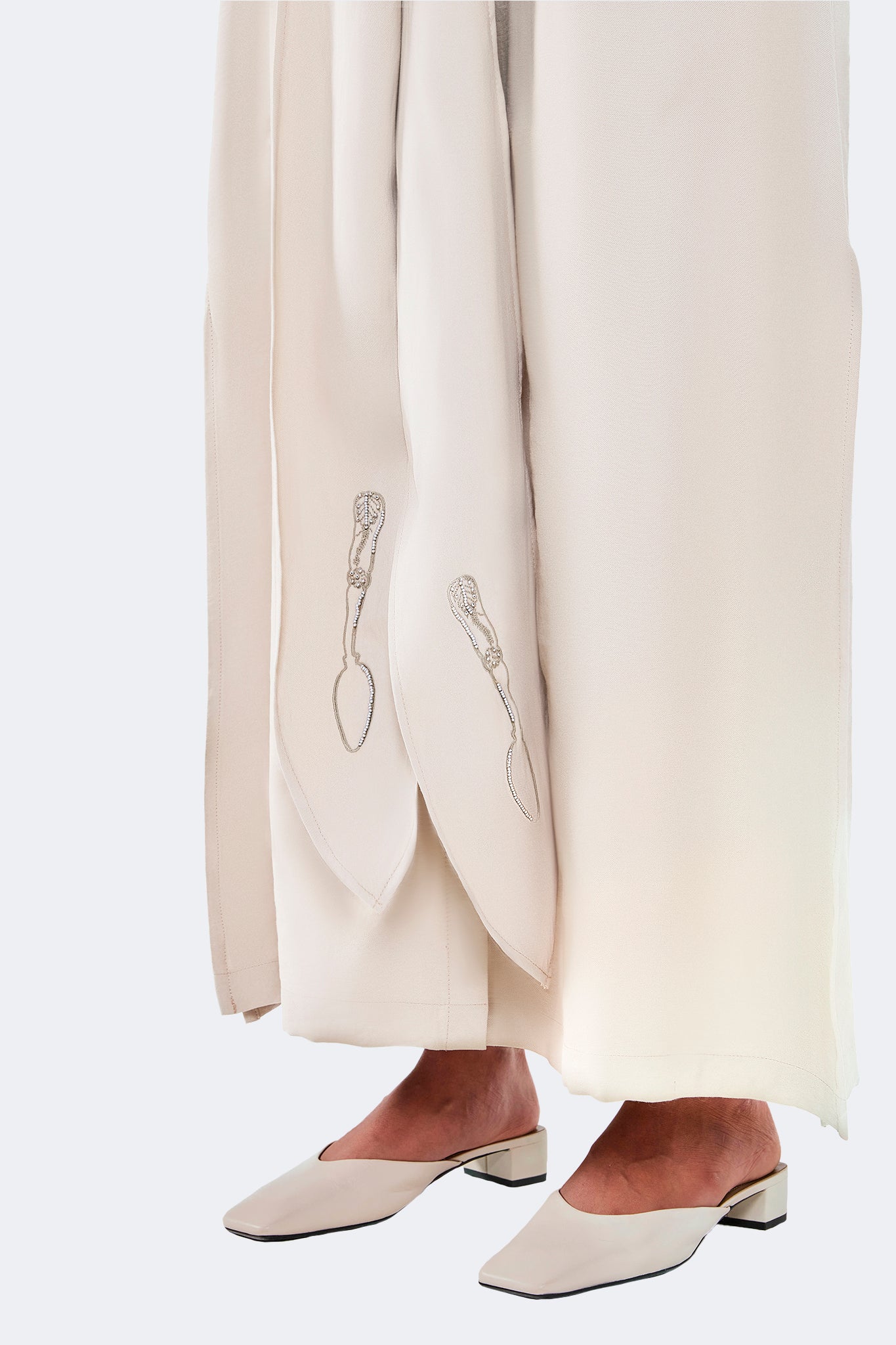Close-up of the Zigze Knotted Dress in Ivory showing archive-inspired embroidered accents on the elongated front ties and soft woven fabric.